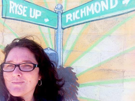 Kimberly Aceves in front of painting with words "Rise Up Richmond."