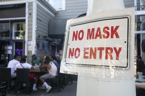 Sign that says NO MASK NO ENTRY in red letters posted at a restaurant with outdoor seating.