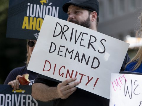 Man at rally holds sign that says "Drivers demand dignity!"
