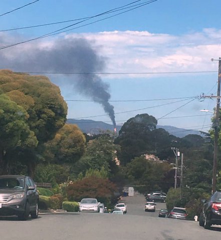 View on a Richmond street of a plume of black smoke in the distance