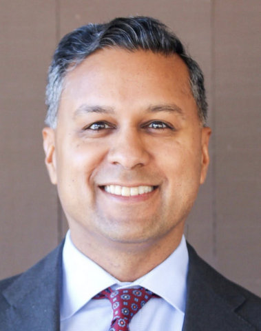 A smiling man of Indian descent in suit and tie.