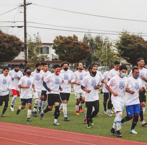 Men in medical-style face masks run on a field.