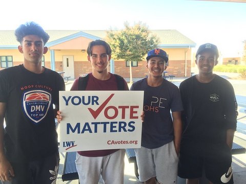 Four young men with one holding sign that reads "Your vote matters" with a checkmark in place of the "v." Other text says LWV and CAvotes.org.