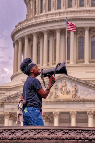 Black person with bullhorn in front of U.S. Capitol