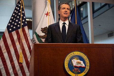 Gov. Gavin Newsom at lectern with California seal in front of U.S. and California flags