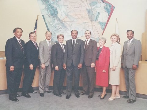 Seven men and two women in suits standing in a row