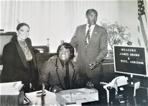 Black-and-white photo of James Brown, his wife Adrienne, and Mayor George Livingston