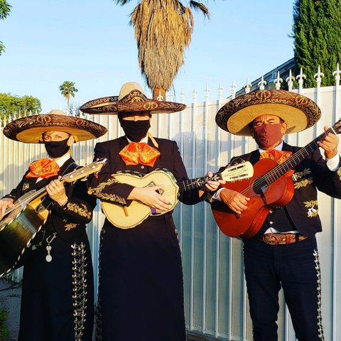 Three mariachis wearing sombreros and face masks