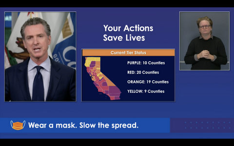 Screenshot with Gavin Newsom, ASL interpreter and color-coded California map. Text reads: Your action saves lives; purple: 10 counties; red: 20 counties; orange: 19 counties; yellow: 9 counties; wear a mask. Slow the spread.