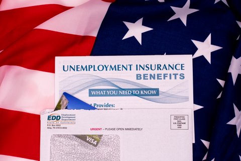 Text: Unemployment Insurance Benefits What You Need to Know. EDD envelope against U.S. flag