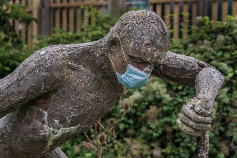 Statue of a man with a surgical mask on its face