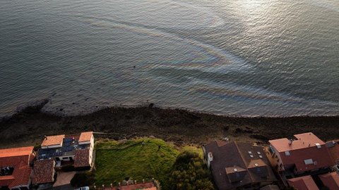 Overhead view of body of water with oil slick causing rainbow sheen