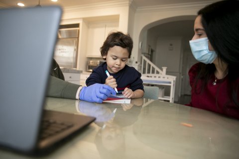 4-year-old boy, woman in medical mask and person in medical gloves at a table.