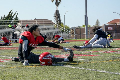Players stretch on the field during a high school football practice.