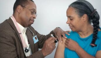 Black man gives vaccine shot in Black woman's arm