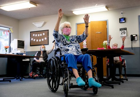 White-haired woman in wheelchair with arms raised