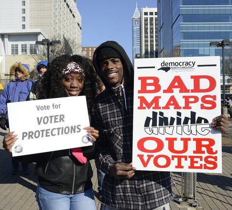 Black woman with sign that says "Vote for voter protections" and Black man with sign that says "Bad maps divide out votes."