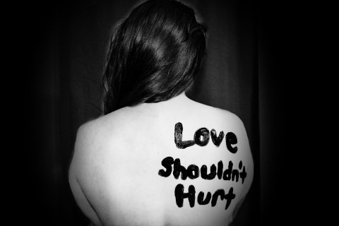 Woman with "love shouldn't hurt" written on her back