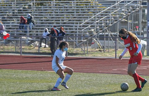 Girls soccer player with the ball and opponent nearby