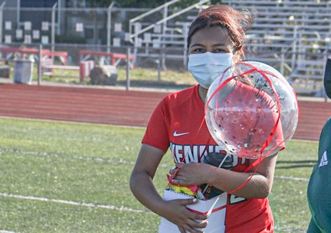 Young woman in white mask and red Kennedy T-shirt holding clear balloon