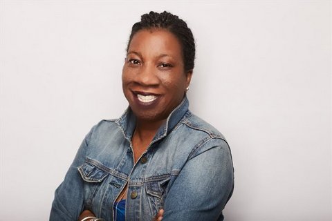A smiling Black woman with short hair and a denim jacket
