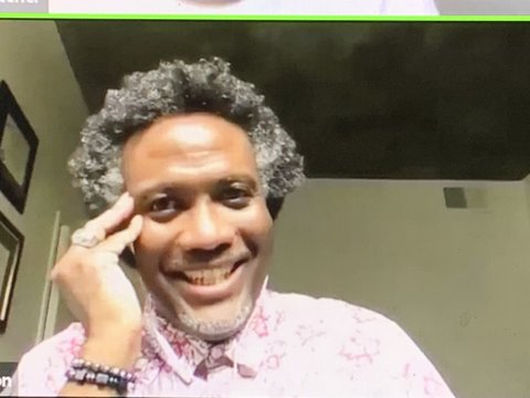 A smiling Black man with salt-and-pepper hair and pink shirt.