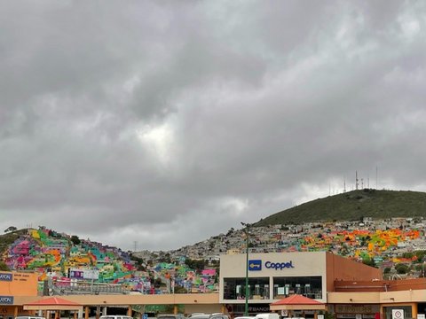 Hills with brightly colored buildings and gray clouds overhead