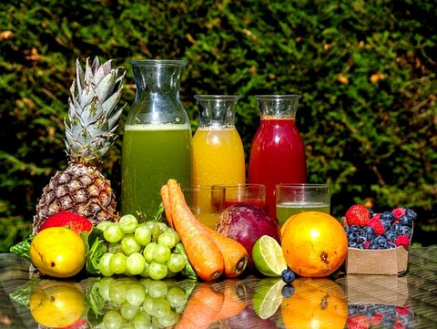 Fruits and vegetables on a table with three glass carafes of different juices
