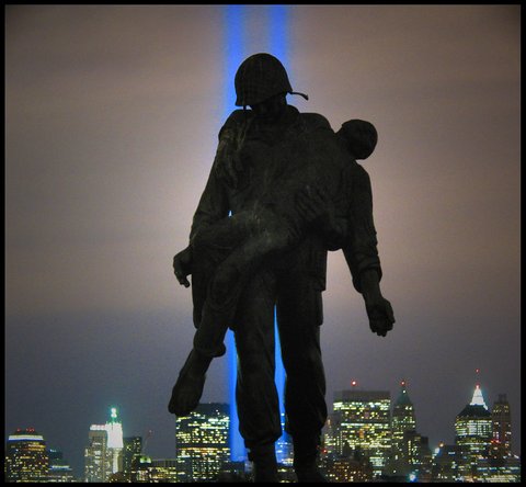 Silhouette of a soldier carrying someone with New York City and two vertical blue lights in the background