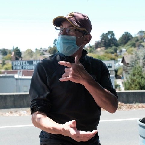 Older white man in ball cap, glasses and mask looking off camera