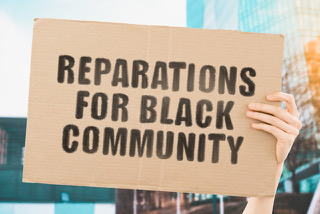 Illustration of a white hand holding a sign that reads "reparations for black community"