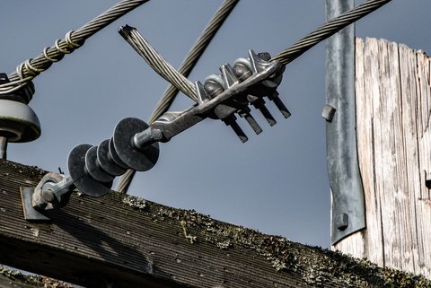 Close view of the insulators and power lines coming out of an electric pole