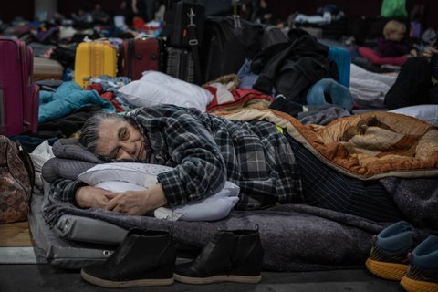 Person laying on a bed in a refugee center