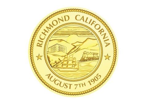 Golden circular seal that says Richmond, California. August 7th 1905. In the middle are pictures of a boat, train, building and hills