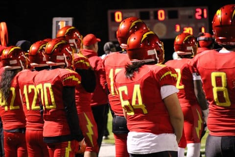 Football players in red uniforms with yellow numbers