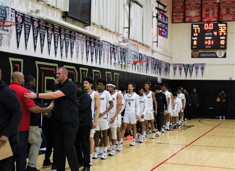 Players and coaches lined up for post-game handshakes following a high school boys basketball game