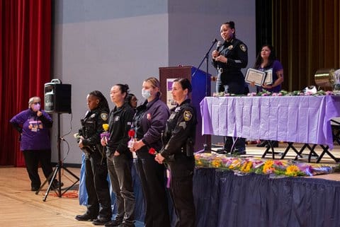 Women in uniform in front of a stage. The women work for police or fire departments.