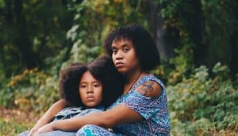 A Black woman and girl sitting together with serious expressions