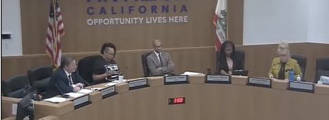 Five people in city council meeting. The words "California opportunity lives here" are visible behind them, along with the U.S. and California flags.