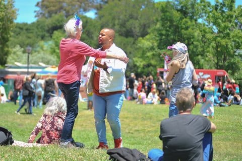 An older white woman and younger Black man about to embrace at a park