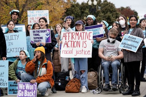 Group of young adults holding signs with messages such as "affirmative action is racial justice," "asian americans for affirmative action," "do the right thing, supreme court" and "we won't go back." Two people are wearing N95 masks, including one in a wheelchair