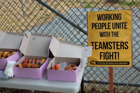 Boxes of doughnuts on a table next to a sign that reads "working people unite with the teamsters fight"