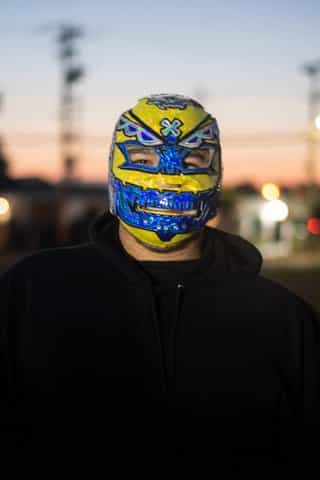 A man in a blue and yellow wrestling mask pulled over his head.