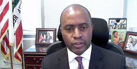 Tony Thurmond, a Black man in a suit, sitting in his office