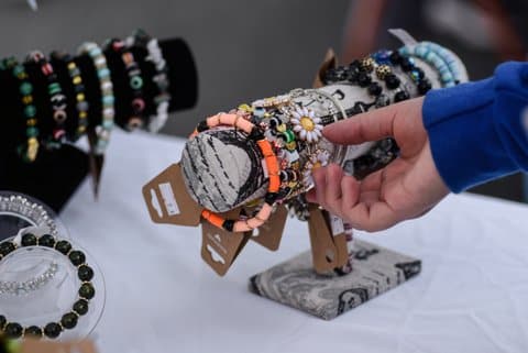 A hand gestures to bracelets on display
