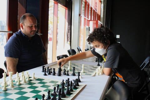 A boy in a mask makes a move on the chess board