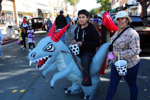 A woman and her son, who is in a costume that makes it look like he is riding an inflatable dragon