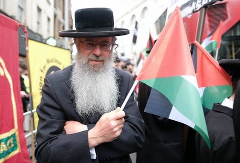 An Orthodox Jewish man holding a Palestinian flag