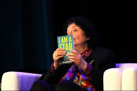 An older Jewish woman holding up her children's book "I am a star"