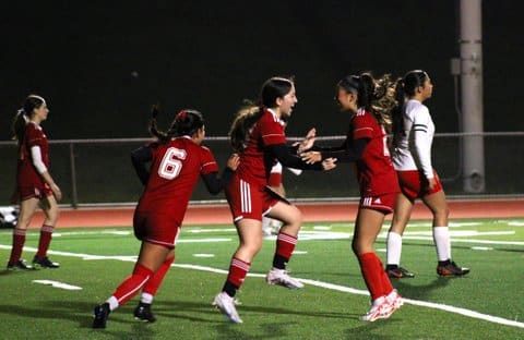 Girls' soccer players celebrating after a goal